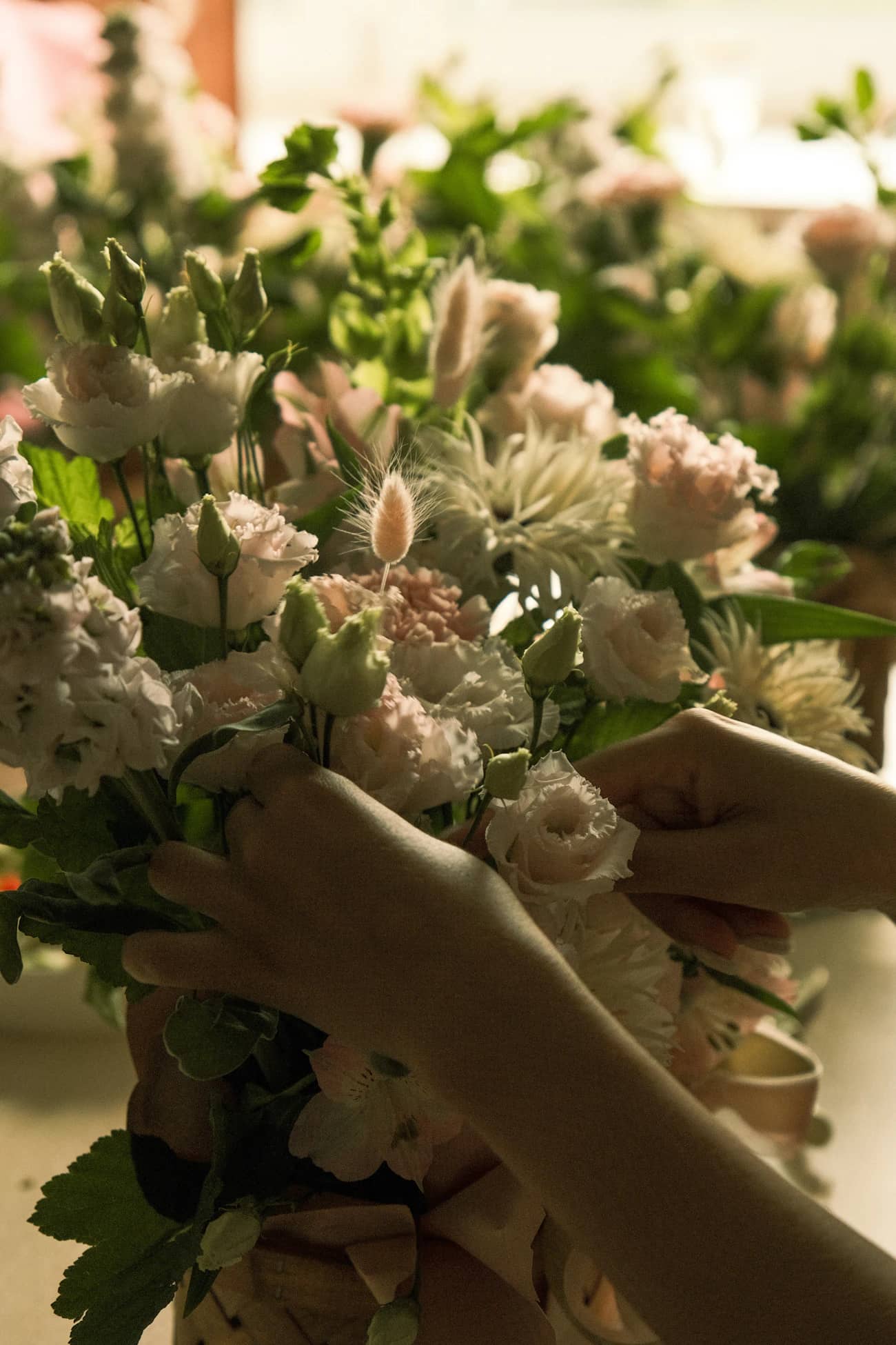 Mâini care leagă un buchet roz